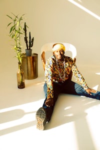 a man sitting on the floor in front of a plant